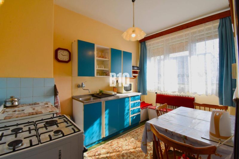 A kitchen in a family house with a blue kitchen unit, a gas stove, and a dining table.