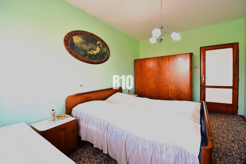 A bedroom in a family house with solid wood furniture and a decorative painting on the wall.