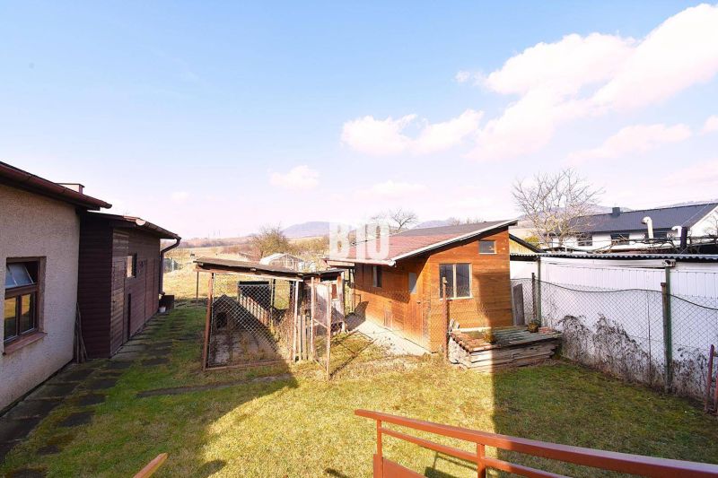 A garden at a family house in Žilina with a wooden extension and a view of the countryside.