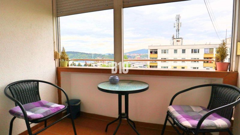 A balcony with a view of Žilina from a 4-room apartment, two chairs, a table.