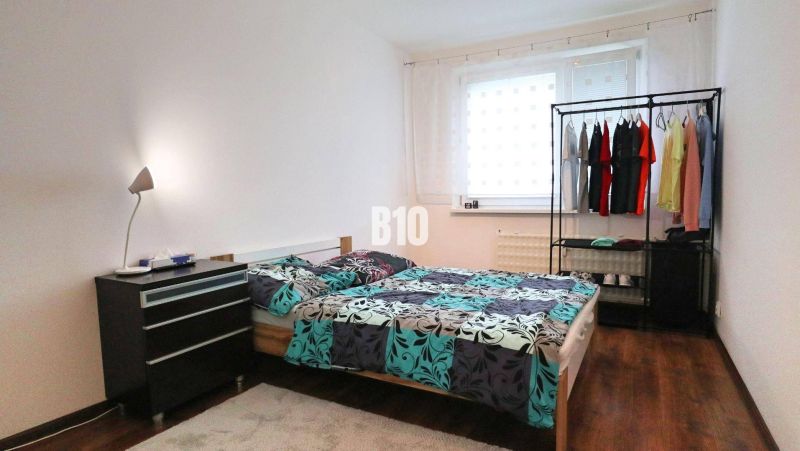 Bright bedroom in a 4-room apartment with a bed and wood-patterned flooring.
