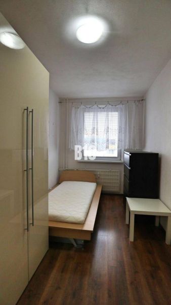 A simply furnished room with a single bed and a wooden-patterned floor in a 4-room apartment.