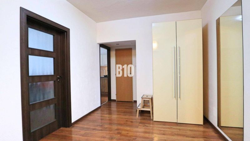 Interior of a 4-room apartment with a wooden decor floor, wardrobe, and mirror.