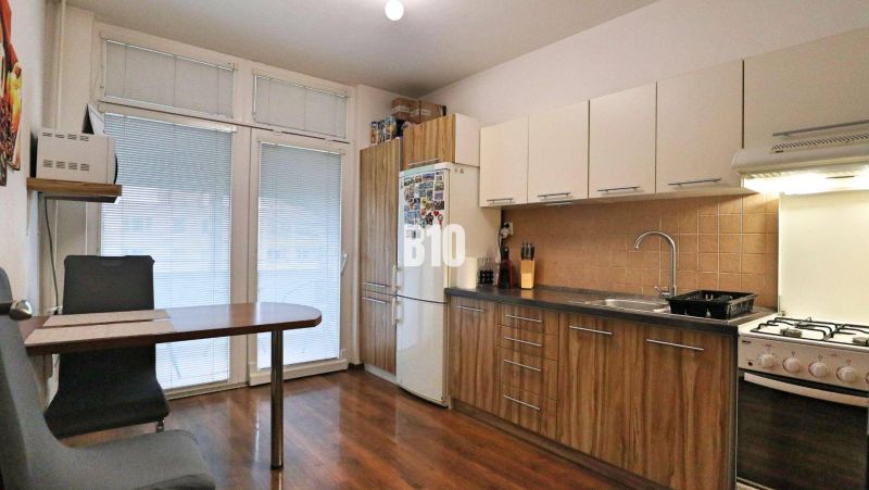 A kitchen in a 4-room apartment with a wood-patterned floor and a dining area.