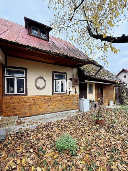 A family house in Kotešová with old wooden cladding and falling leaves in the garden.