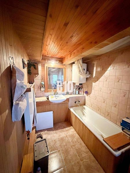 A bathroom in a family house with wooden paneling and a bathtub.