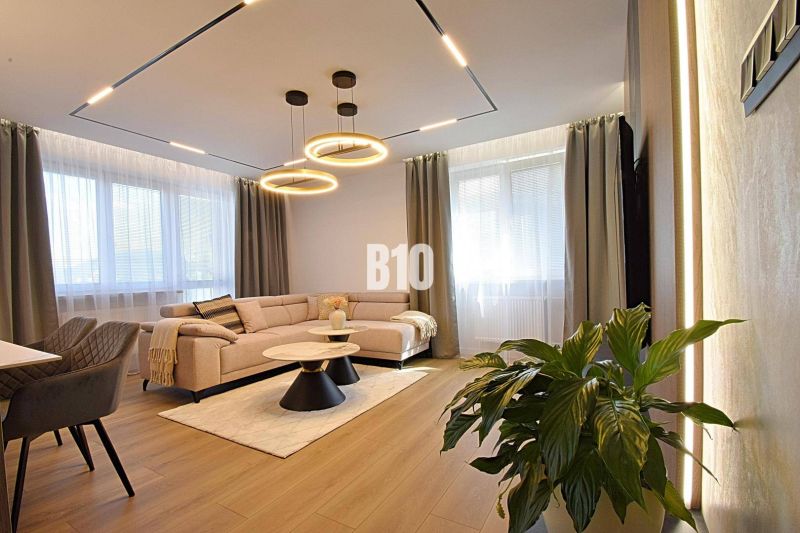Living room in a 3-room apartment with a wooden decor floor, a light couch, and a plant.