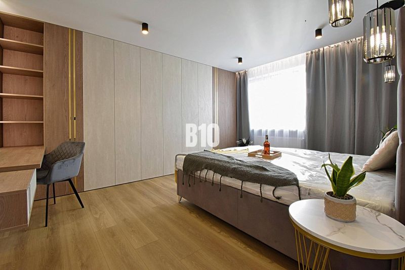 A bedroom with a desk, bed, and floor with a wooden decor in a 3-room apartment.