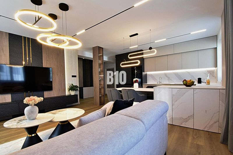 Living room in a 3-room apartment with wood-patterned flooring and stylish lighting.