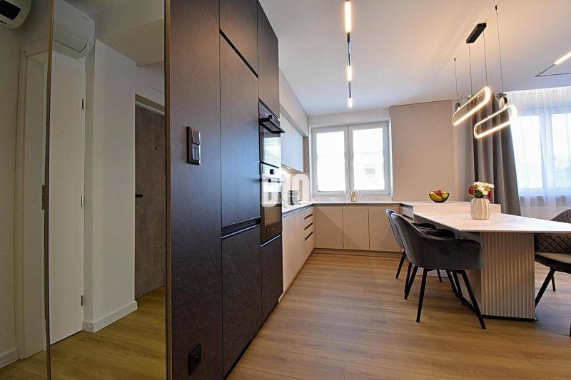 A kitchen in a 3-room apartment with a dining table and a floor with a wood decor.