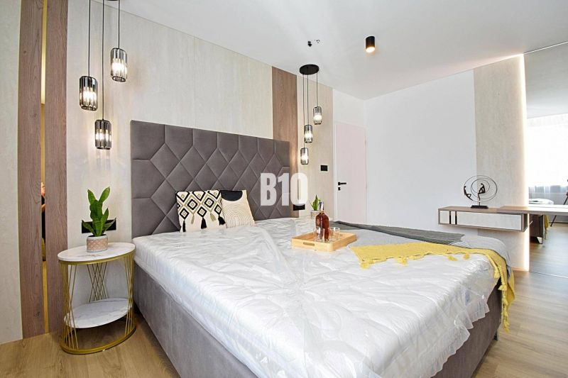 Bedroom in a 3-room apartment with a large bed, hanging lamps, and a wooden decor floor.