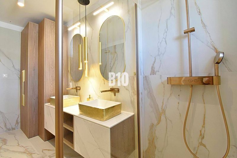 Luxury bathroom with marble tiles and gold accessories in a 3-room apartment.