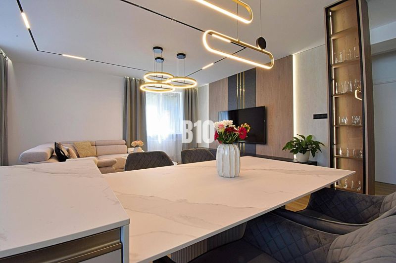 Living room in a 3-room apartment with wood-patterned flooring, a couch, and interesting lighting.
