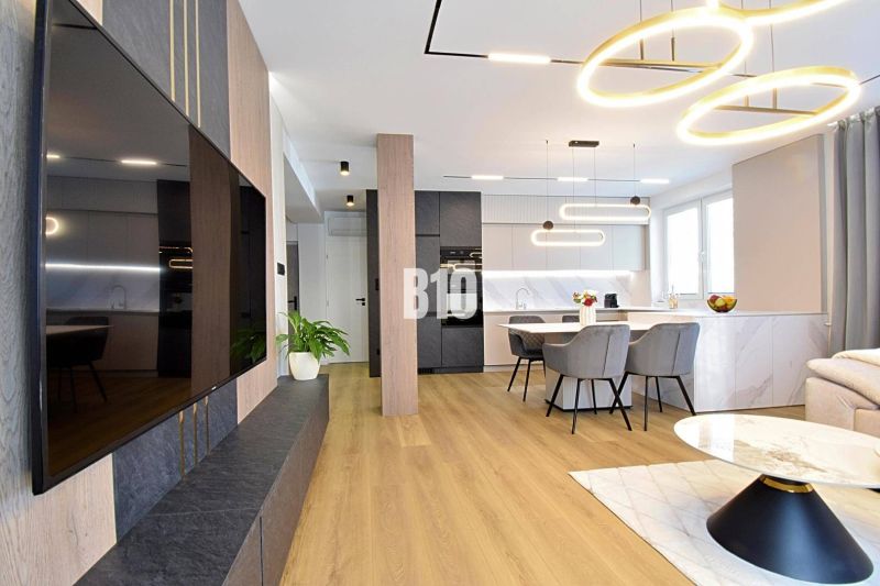 Living room in a 3-room apartment with a wooden decor floor, dining table, and television.