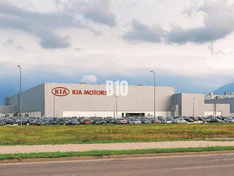 Kia Motors building in Žilina, commercial land with parked cars and grassy area.