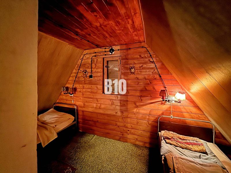 A rustic interior of a cabin with two beds and wooden paneling on the walls.