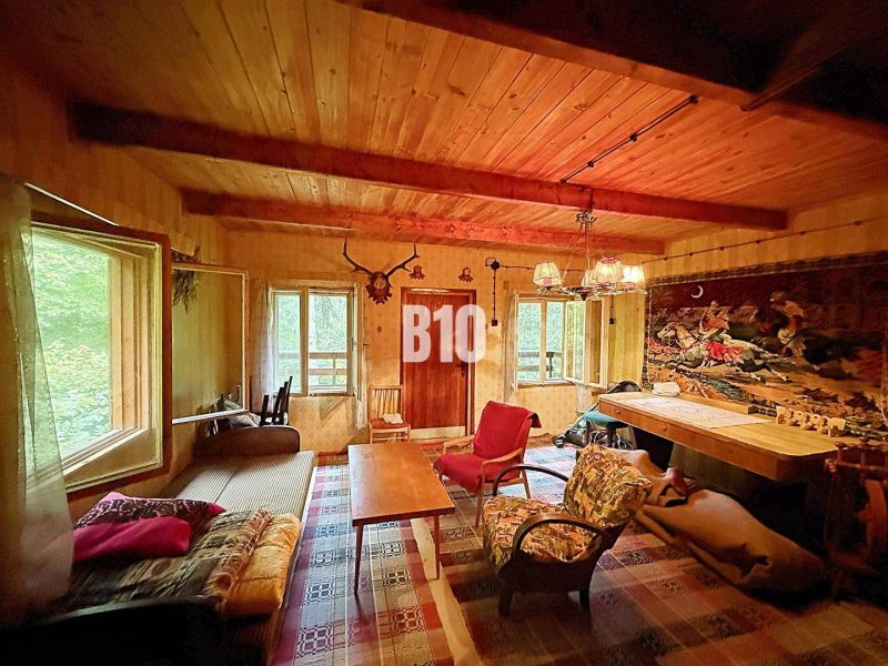The interior of a cabin with a wooden ceiling, comfortable seating, and a decorative carpet on the wall.