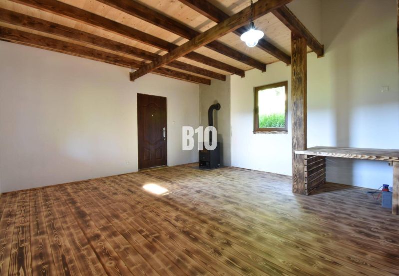 Interior of a cabin with a wooden ceiling, floor, and stove.