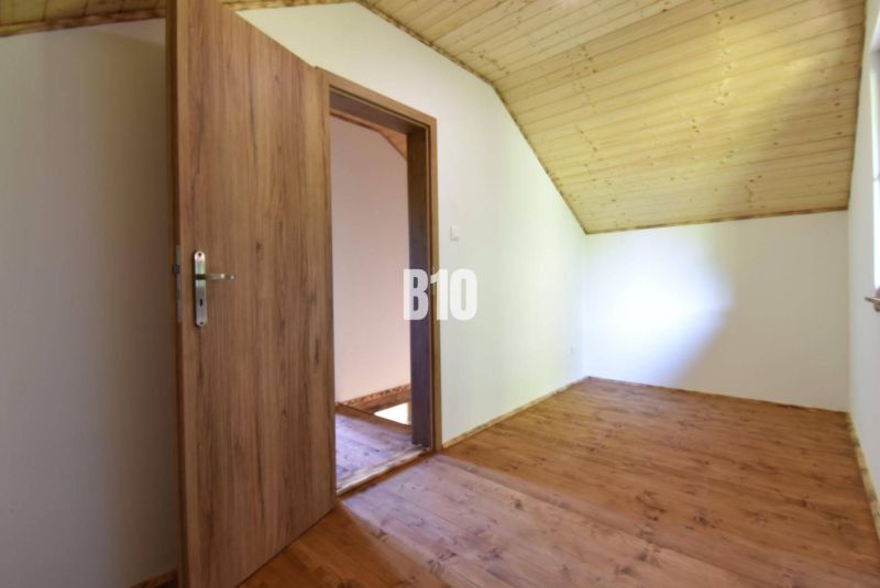 A room in a cottage with wooden doors and a wooden floor.