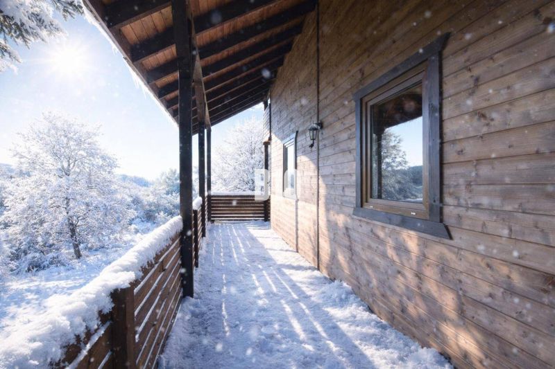 A snowy terrace of a wooden cabin in Bytča with a view of the winter landscape.