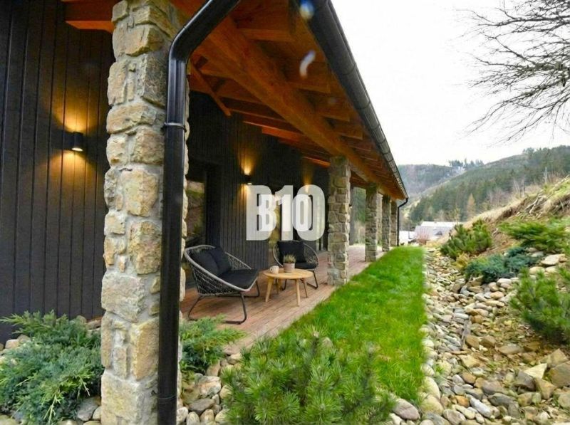 Covered terrace of the cottage in Horná Mariková with stone pillars and comfortable seating.