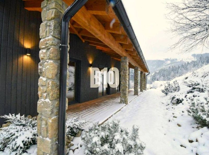 A cottage in the snowy landscape of Horná Mariková with stone pillars and wooden decor.
