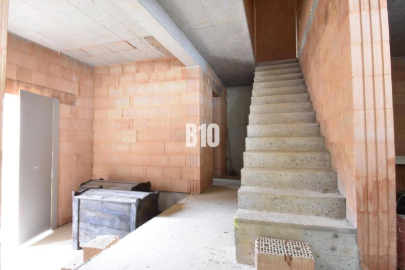 Interior of an unfinished residential house with a staircase and bricks for construction.