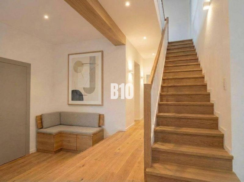 Interior of a cabin with wooden decor, stairs, bench, painting, neutral colors.
