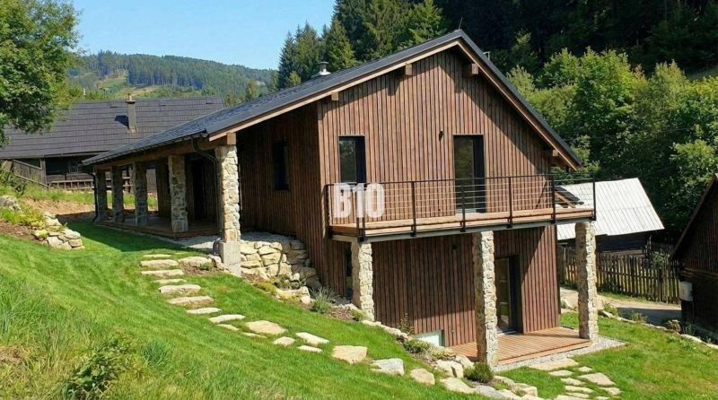 A wooden cottage in Horná Mariková surrounded by greenery and hilly landscape.