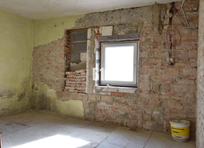 A room in a family house with brick walls and a bucket on the floor.
