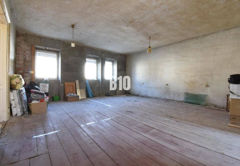 A spacious room in a family house with wooden flooring and unfinished walls.