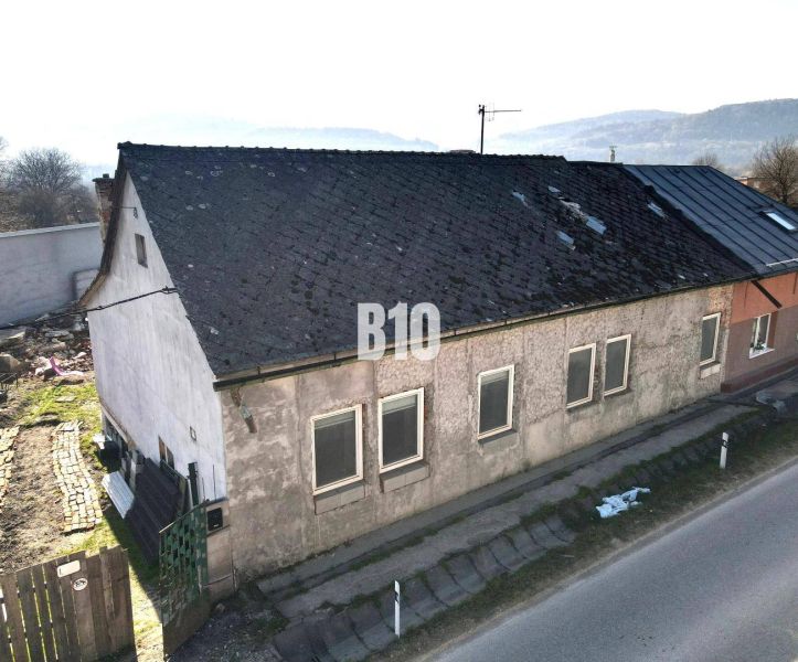 A family house in Bytča with a worn-out roof and plaster, next to the main road.