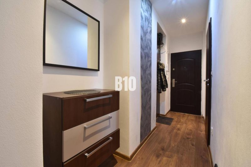 A hallway with a mirror, a chest of drawers, and a wooden decor floor in a 3-room apartment.