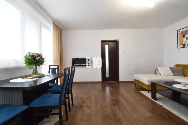 Living room in a 3-room apartment with wooden decor and a dining table.