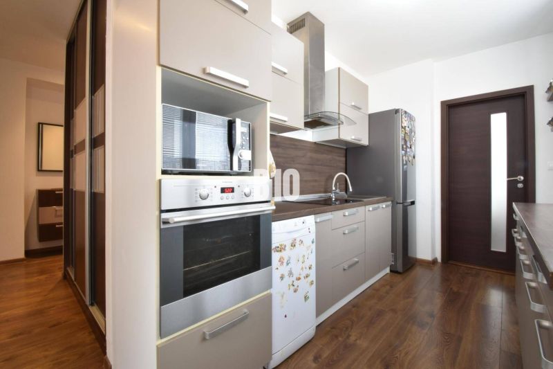 A kitchen in a 3-room apartment with a wooden decor floor and modern equipment.