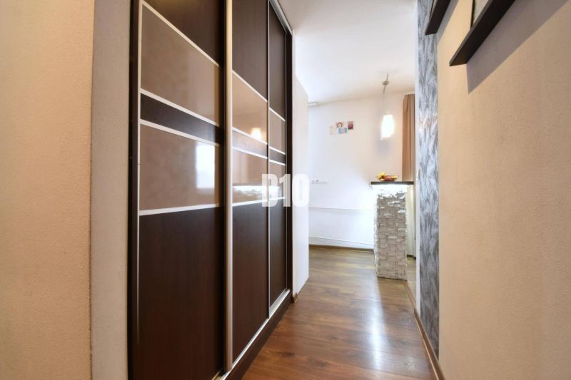 A hallway in a 3-room apartment with a wooden decor floor and a built-in wardrobe.