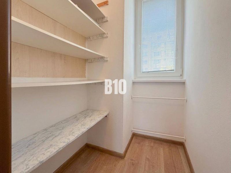 A small room in a vacation apartment with shelves and a window, floor with wood decor.
