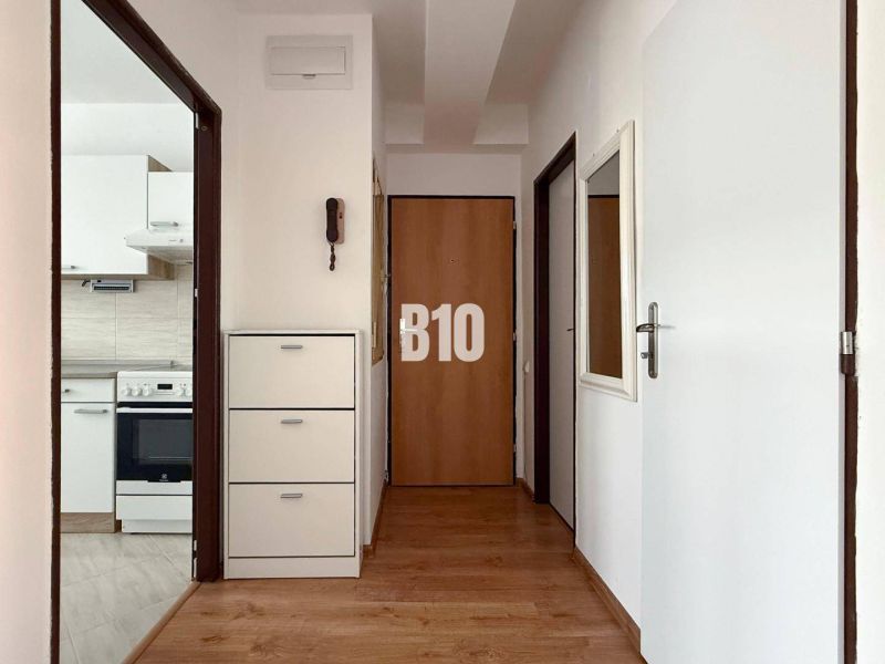 A hallway with a wooden decor floor in a Holiday Apartment, with a kitchen in the background.