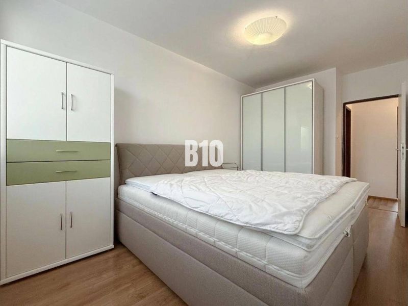 A bright room in a holiday apartment with a bed, wardrobes, and a wooden decor floor.