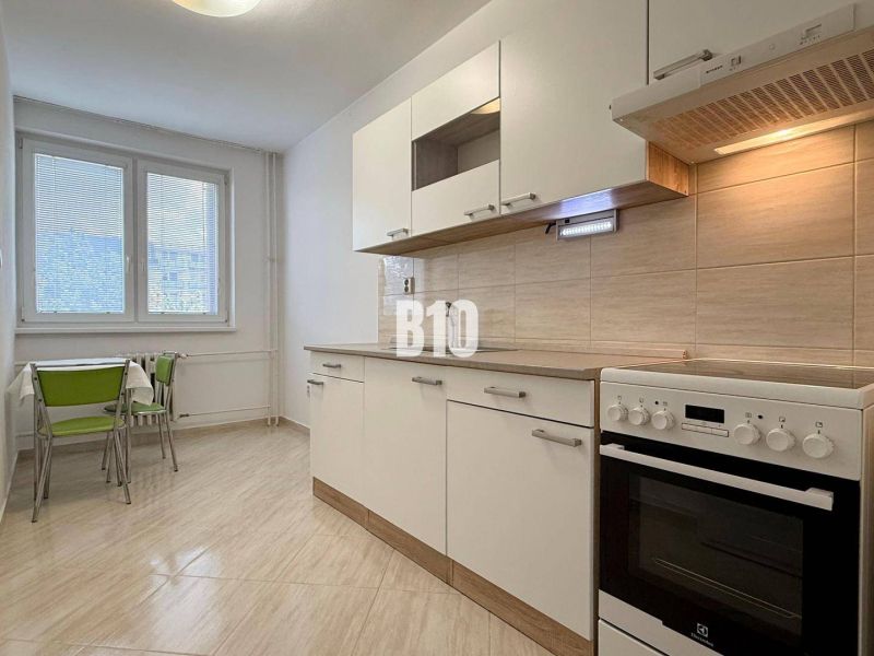 Bright kitchen in a Holiday Apartment with a stove and a table with green chairs.