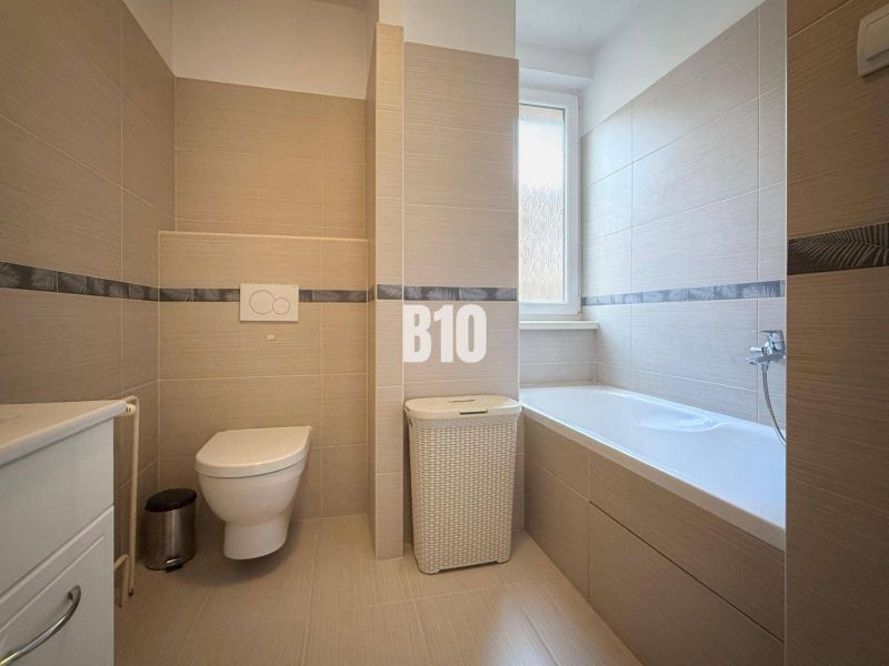 Bathroom in a holiday apartment with a bathtub, toilet, and modern tiles.