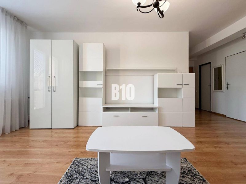 Interior of a holiday apartment with white furniture and a wooden decor floor.