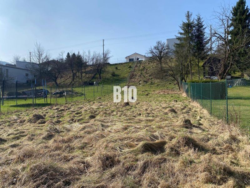 A plot for residential use in Radoľa surrounded by grass and fencing, ideal for construction.