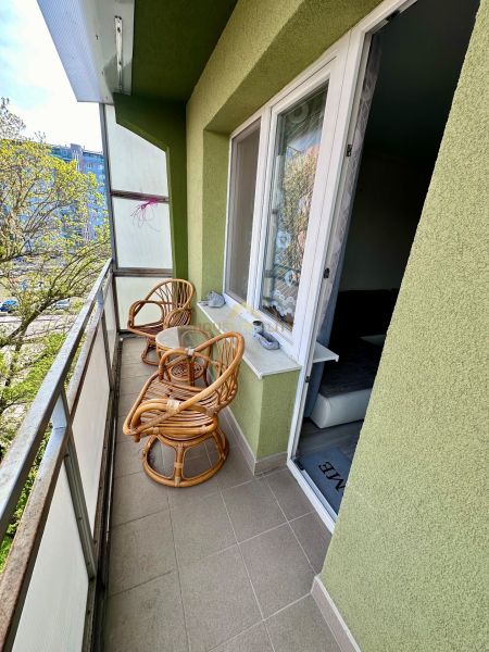 Balcony with two rattan chairs and a table, view of greenery, 3-room apartment.