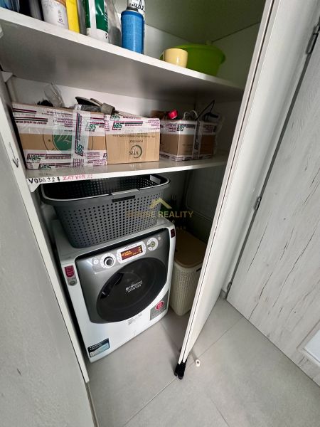 Storage space in a 3-room apartment with a washing machine and shelves.