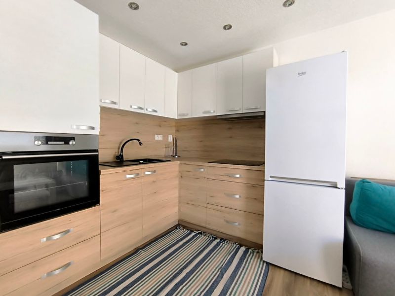 A kitchenette in a one-room apartment with a wooden decor floor and appliances.