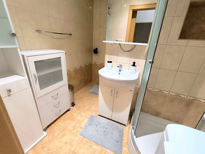 A bathroom with a bathtub, sink, and storage cabinets in a studio apartment.