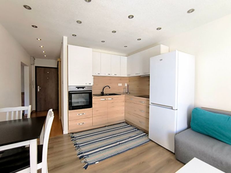 A kitchen in a studio apartment with a wood-patterned floor and white cabinets.