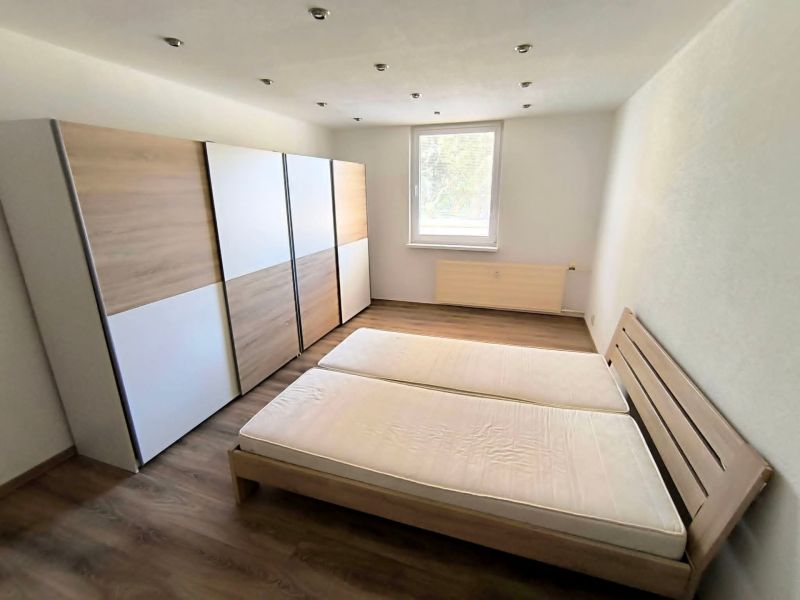 Bedroom with a large wardrobe, double bed, and wooden decor flooring in a studio apartment.
