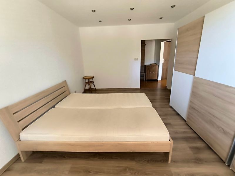 A bedroom in a studio apartment with a bed and a wooden decor floor.